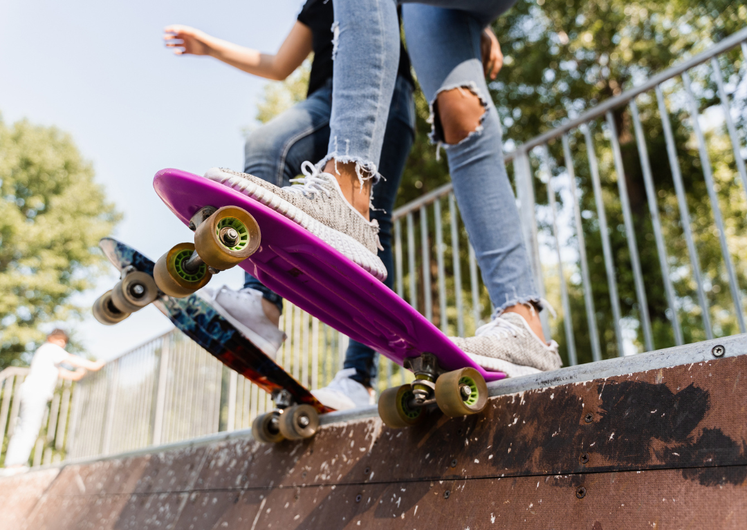 Two skateboarders on the ledge of a ramp, ready to skate on their penny boards.